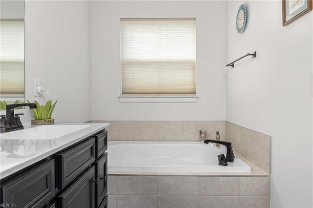 bathroom with a garden tub, vanity, and a healthy amount of sunlight