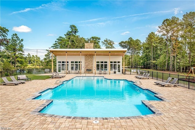 community pool with a patio area and fence