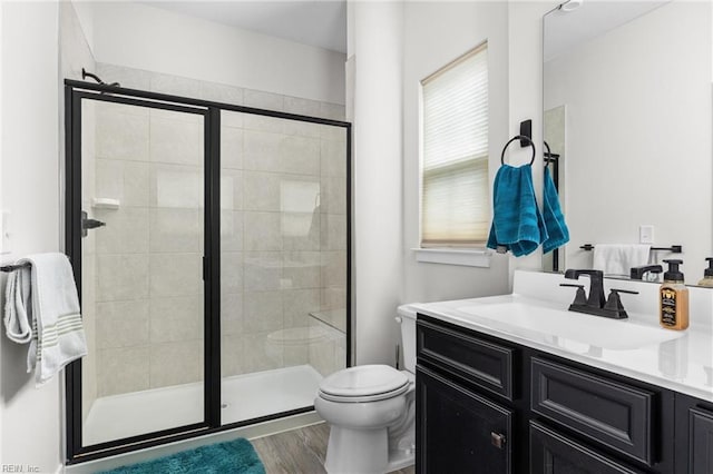 full bathroom featuring wood finished floors, a stall shower, vanity, and toilet