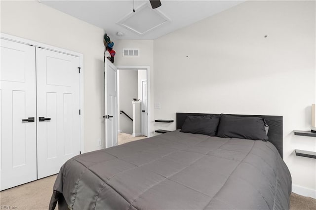 bedroom featuring a closet, visible vents, attic access, a ceiling fan, and light carpet