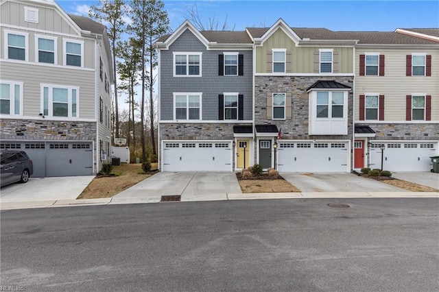 townhome / multi-family property with a garage, stone siding, board and batten siding, and driveway