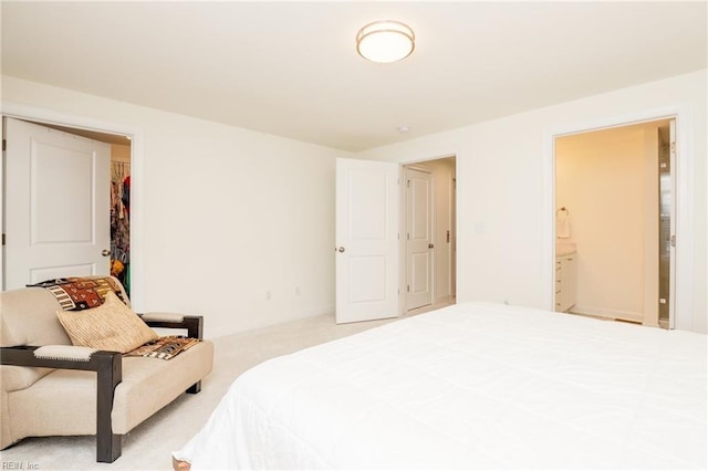 bedroom featuring a walk in closet, light colored carpet, and connected bathroom