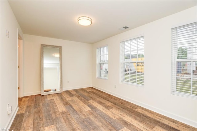 empty room featuring visible vents, baseboards, and wood finished floors