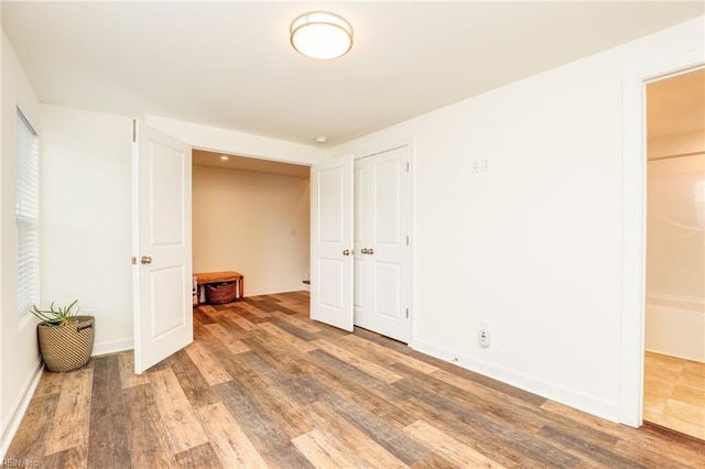 unfurnished bedroom featuring a closet, wood finished floors, and baseboards