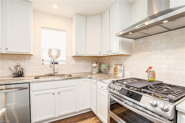 kitchen with appliances with stainless steel finishes, white cabinets, a sink, light stone countertops, and exhaust hood