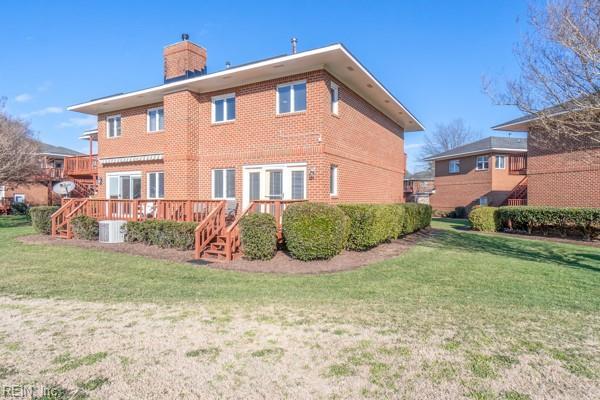 view of side of home with brick siding, a chimney, a lawn, central AC, and a deck