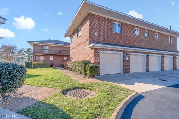 view of side of property with driveway, brick siding, and a lawn