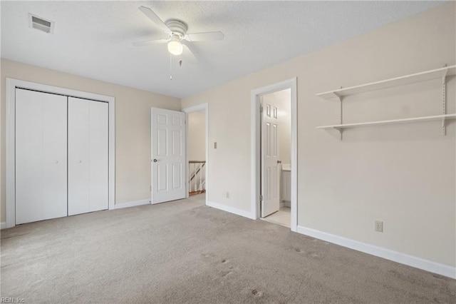 unfurnished bedroom featuring light carpet, baseboards, visible vents, a textured ceiling, and a closet