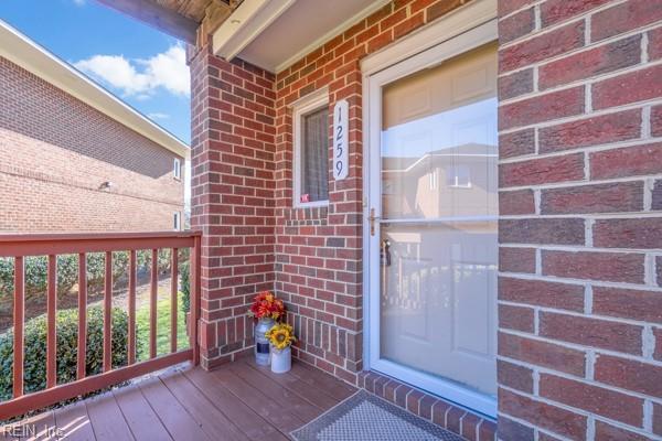 doorway to property with covered porch and brick siding