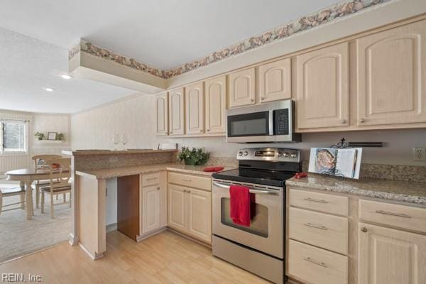 kitchen with a peninsula, light wood-style floors, stainless steel appliances, and light countertops