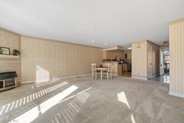 unfurnished living room with light carpet, wallpapered walls, a fireplace, and baseboards