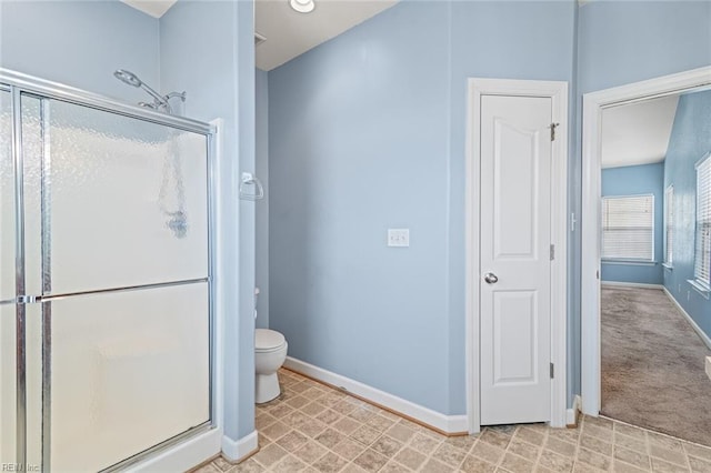 bathroom featuring a closet, a shower stall, toilet, and baseboards