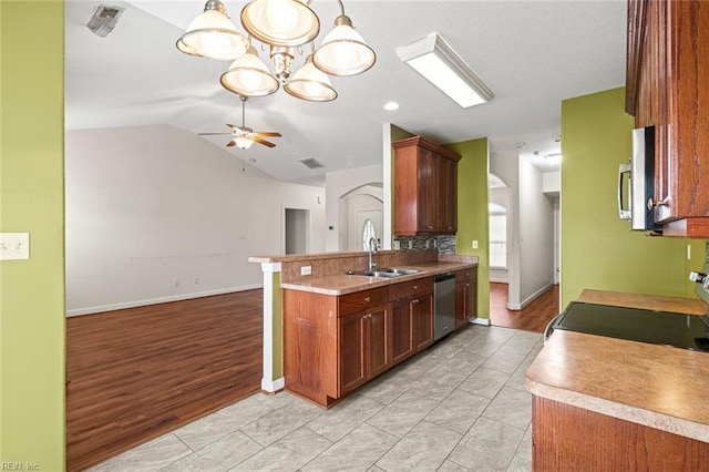 kitchen with appliances with stainless steel finishes, open floor plan, light countertops, a sink, and ceiling fan with notable chandelier