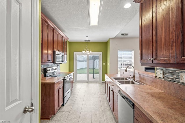 kitchen featuring visible vents, appliances with stainless steel finishes, hanging light fixtures, light countertops, and a sink