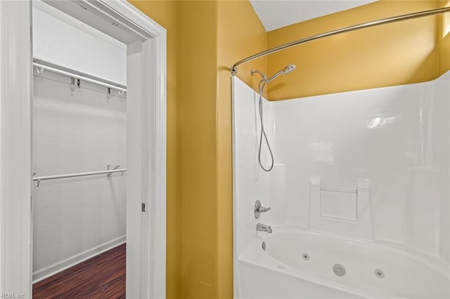 bathroom with a combined bath / shower with jetted tub, baseboards, and wood finished floors