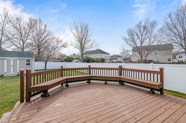 wooden deck with an outbuilding, a lawn, a shed, a residential view, and a fenced backyard