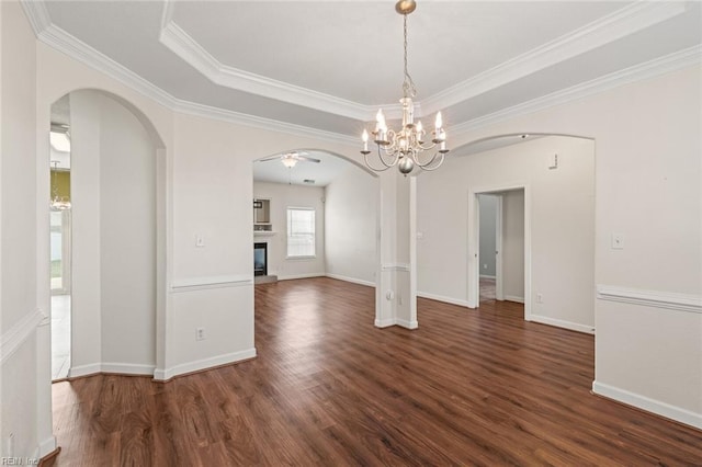 interior space featuring arched walkways, a tray ceiling, dark wood finished floors, a glass covered fireplace, and ceiling fan with notable chandelier