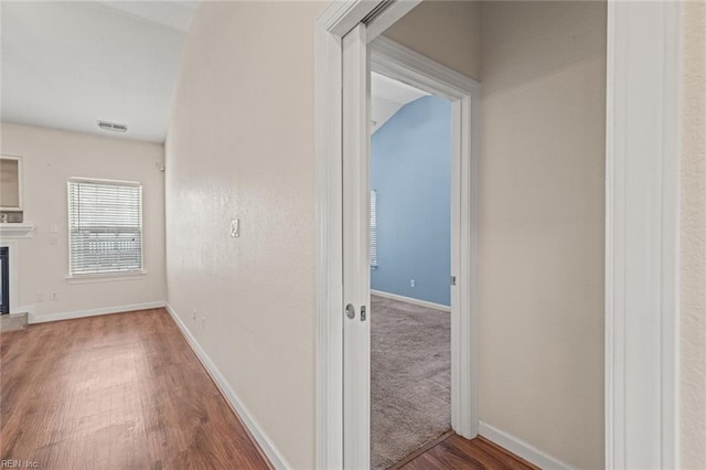 corridor with visible vents, baseboards, and dark wood-style flooring