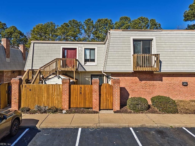 townhome / multi-family property featuring uncovered parking, brick siding, and mansard roof