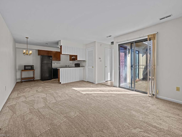 unfurnished living room featuring a chandelier, light colored carpet, visible vents, and baseboards