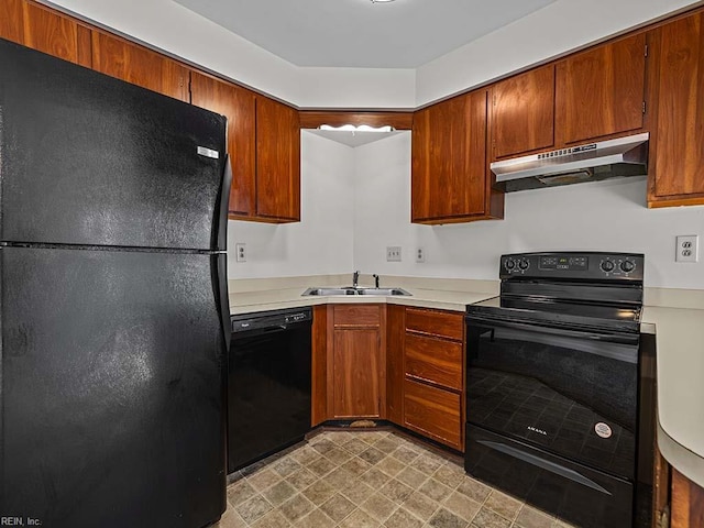 kitchen featuring under cabinet range hood, a sink, light countertops, brown cabinets, and black appliances