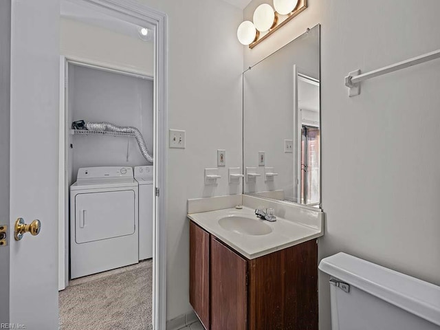 half bathroom featuring toilet, washing machine and clothes dryer, and vanity