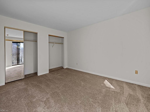 unfurnished bedroom with carpet, baseboards, and two closets