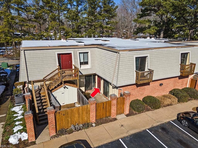 view of front of house with a fenced front yard, cooling unit, brick siding, stairs, and uncovered parking