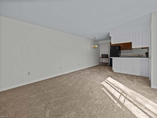 unfurnished living room featuring light carpet, baseboards, a sink, and a notable chandelier