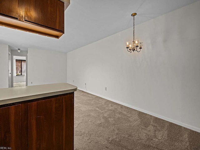 kitchen featuring light colored carpet, baseboards, hanging light fixtures, light countertops, and an inviting chandelier