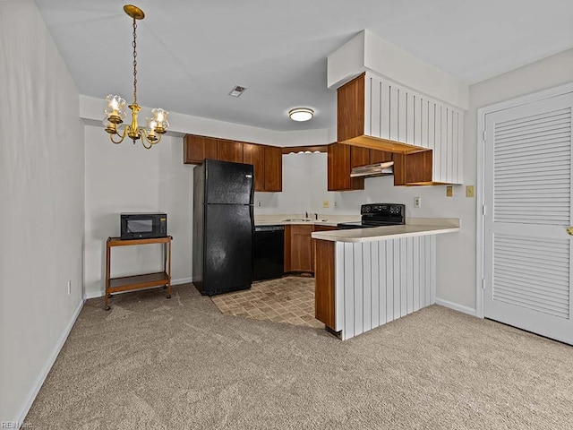 kitchen featuring light countertops, hanging light fixtures, brown cabinetry, a peninsula, and black appliances