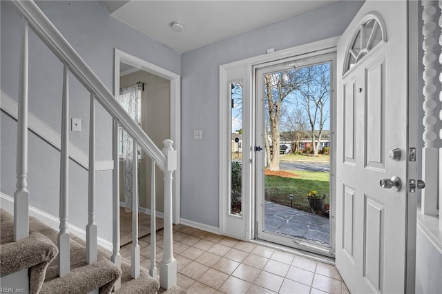 entrance foyer with baseboards, light tile patterned flooring, and stairs