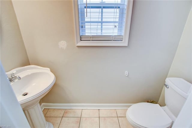 half bath with tile patterned flooring, toilet, and baseboards