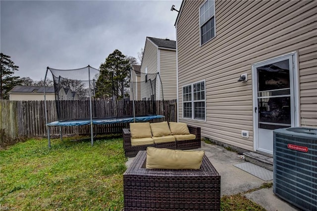 view of yard featuring a trampoline, a patio, an outdoor hangout area, central AC, and a fenced backyard