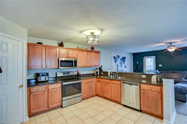 kitchen with appliances with stainless steel finishes, brown cabinetry, open floor plan, a sink, and a peninsula