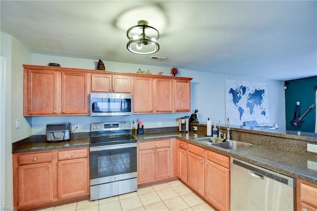 kitchen featuring appliances with stainless steel finishes, dark countertops, and a sink