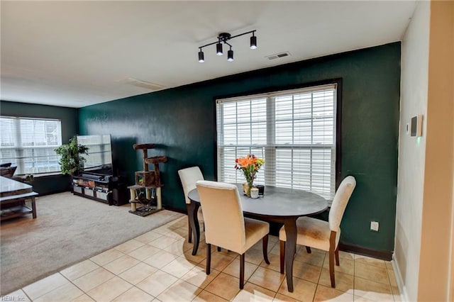 dining area featuring rail lighting, light colored carpet, visible vents, and light tile patterned flooring