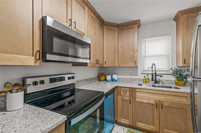 kitchen with appliances with stainless steel finishes, a sink, and light stone countertops