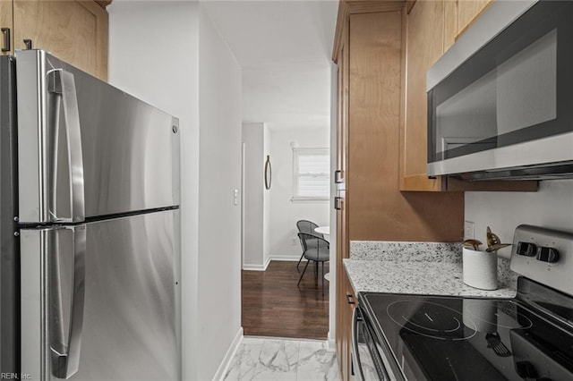 kitchen with appliances with stainless steel finishes, marble finish floor, baseboards, and light stone countertops