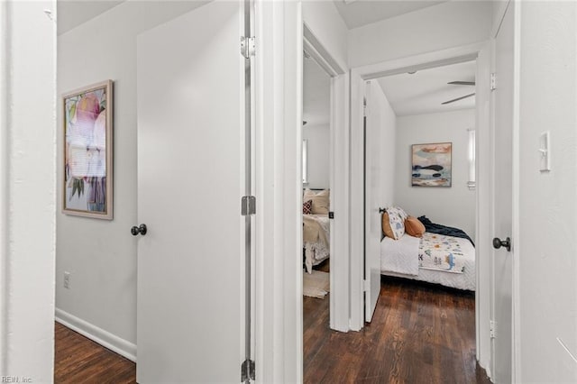 corridor with dark wood-style flooring and baseboards