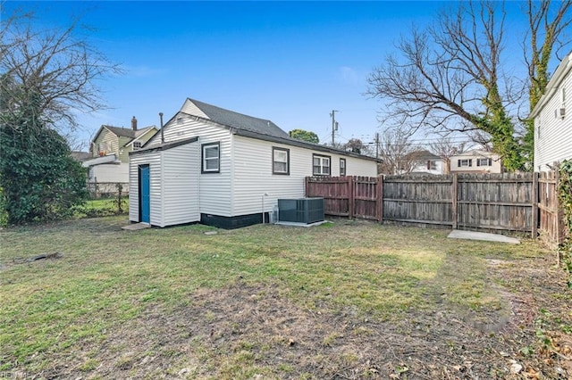 back of house featuring a yard, central AC, and a fenced backyard