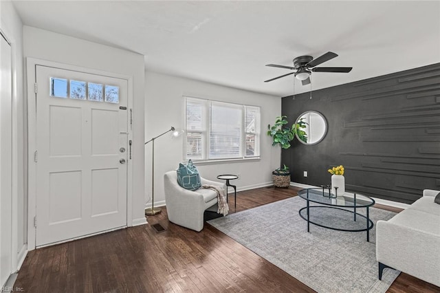 foyer entrance with an accent wall, ceiling fan, baseboards, and wood finished floors