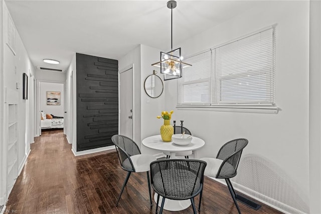 dining room featuring visible vents, baseboards, a chandelier, and wood finished floors