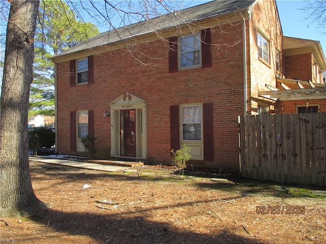 colonial-style house featuring brick siding and fence