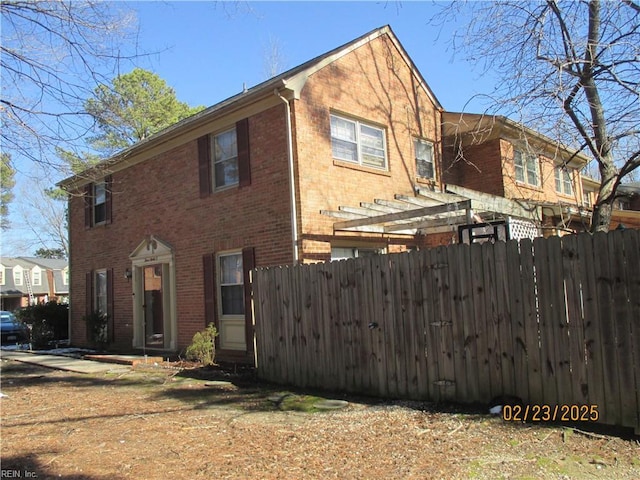 view of home's exterior with fence and brick siding