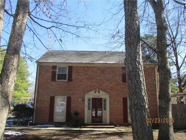 colonial-style house featuring fence, french doors, and brick siding