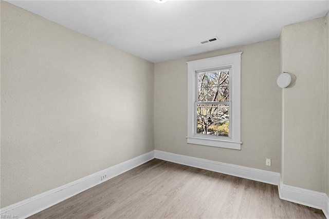 unfurnished room featuring visible vents, baseboards, and wood finished floors