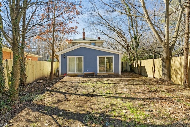 rear view of house with a fenced backyard and a chimney