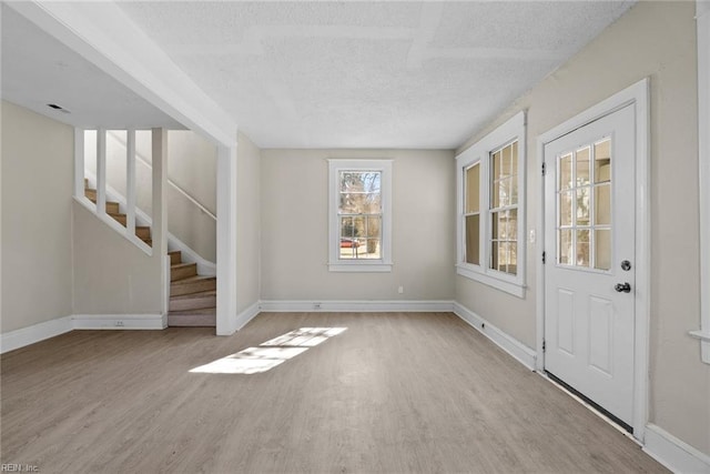 entrance foyer featuring baseboards, stairway, and light wood finished floors