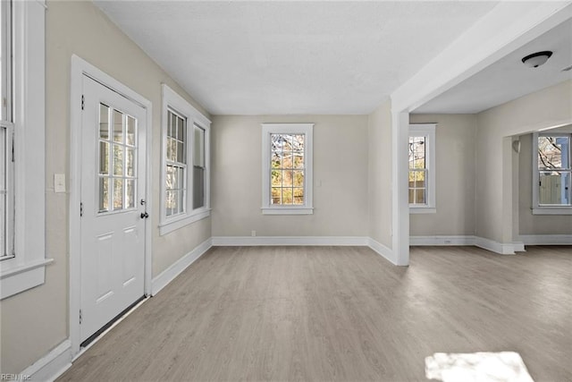 foyer entrance featuring light wood-type flooring, plenty of natural light, and baseboards